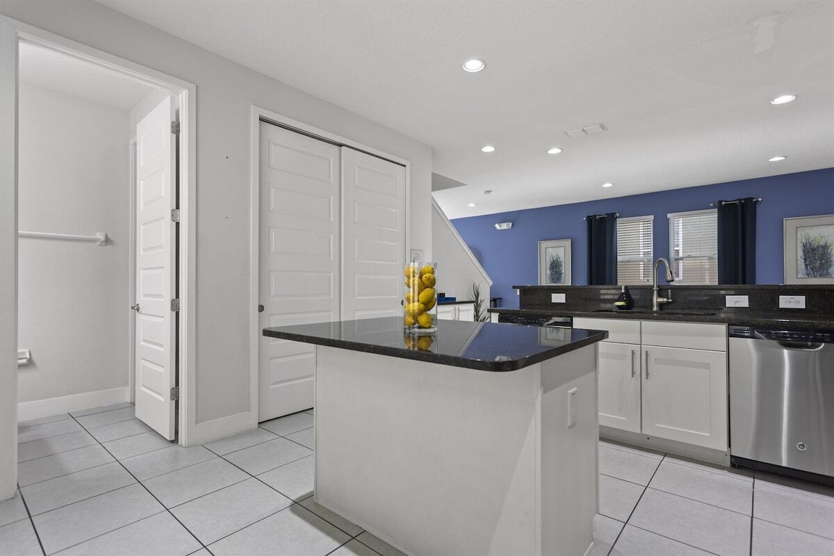 A modern kitchen with white cabinets, a black countertop, and stainless steel appliances.