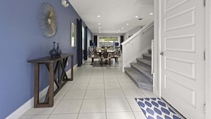 A hallway with a dining area, a staircase, and a white door. - 350-360 Huge Villas - Near Disney - 15 BDs (Kissimmee)