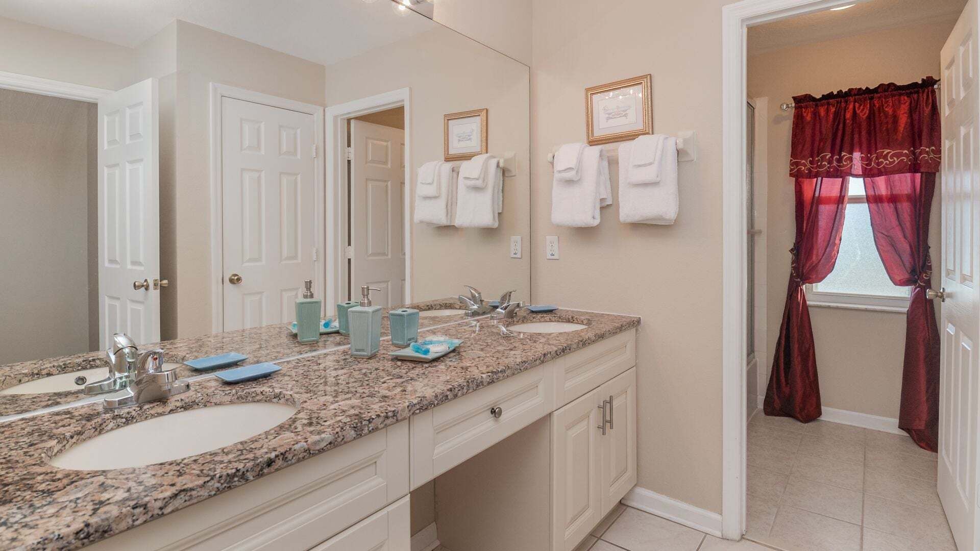 A bathroom with two sinks, a large mirror, and a shower area with red curtains.