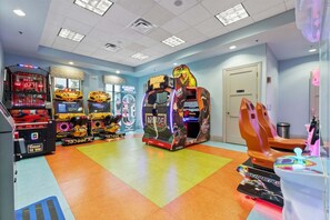 A brightly lit arcade with various gaming machines, a colorful floor, and a door in the background. - Myr1471 (Davenport)