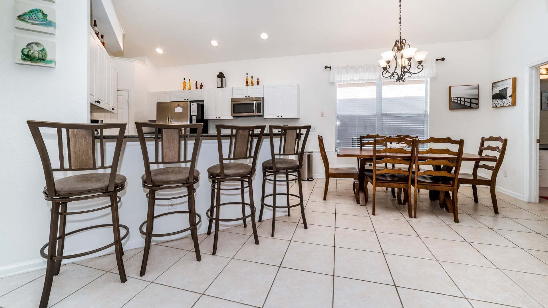 A modern kitchen with white cabinets, a central island, and bar stools.