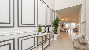 En modern hall med ett konsolbord i marmor, krukväxter och en trappa som leder till ett annat våningsplan.