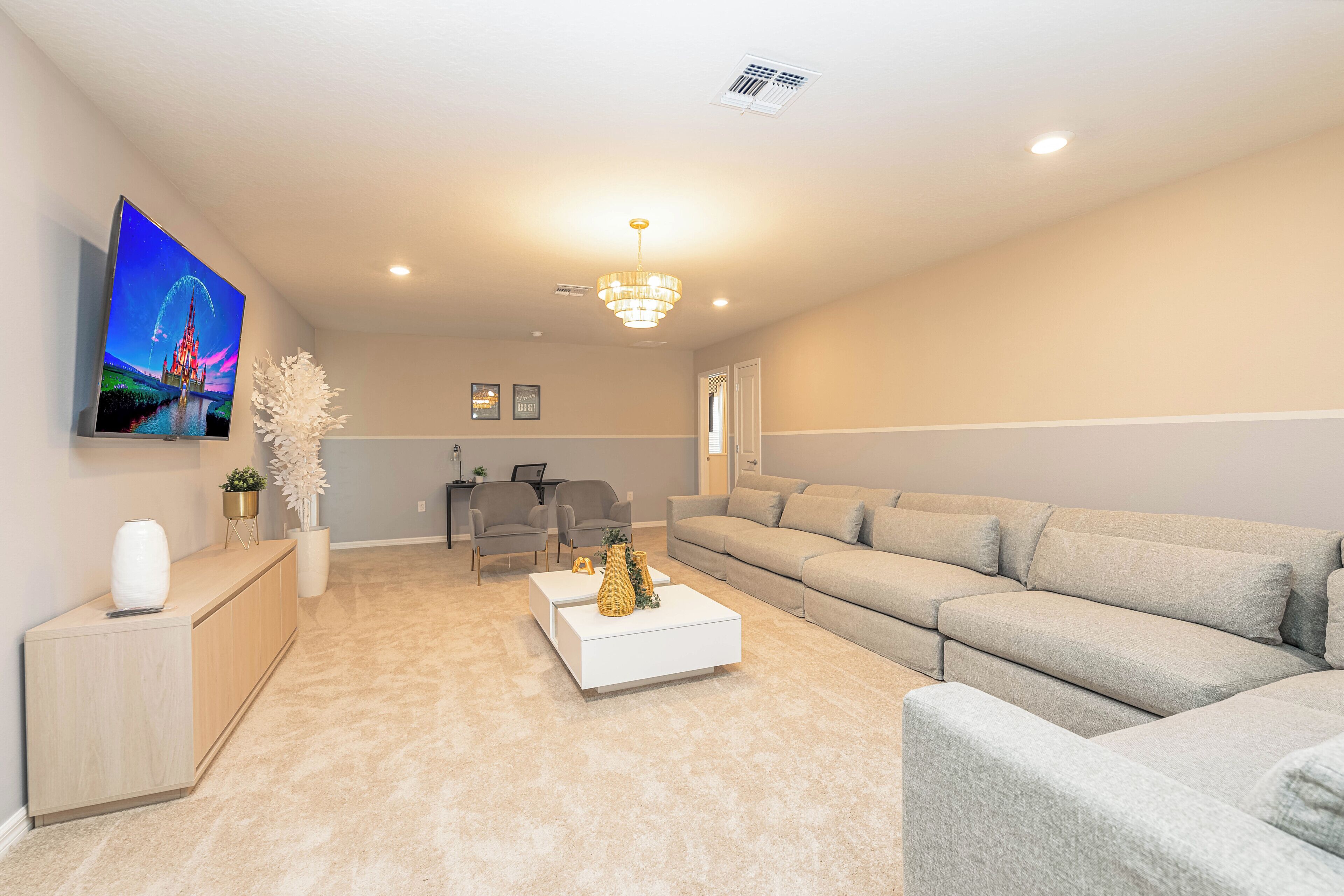 A living room with a TV, sofa, coffee table, and chairs.