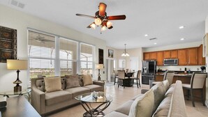 A spacious living room with a sofa, a glass coffee table, and a dining area with chairs. - Windsor Hills Resort 6 Bedroom Private Pool Spa Home 0743 (Kissimmee)