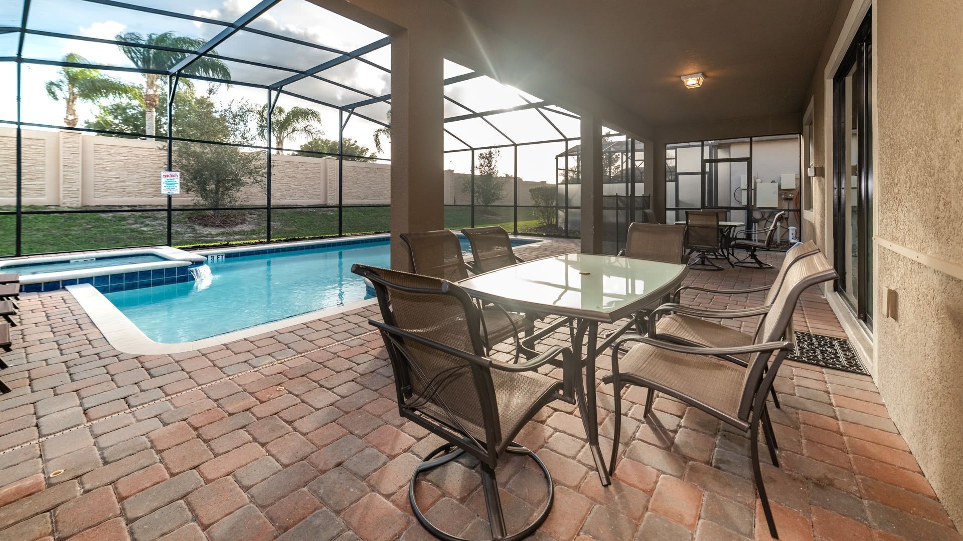 A covered patio with a pool, outdoor seating, and a view of the surrounding area.