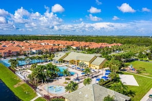 A resort with a swimming pool, multiple buildings with red roofs, and a large lawn area. - Special Offer Stunning Townhome With Private Pool Close to Disney 8960pp (Kissimmee)