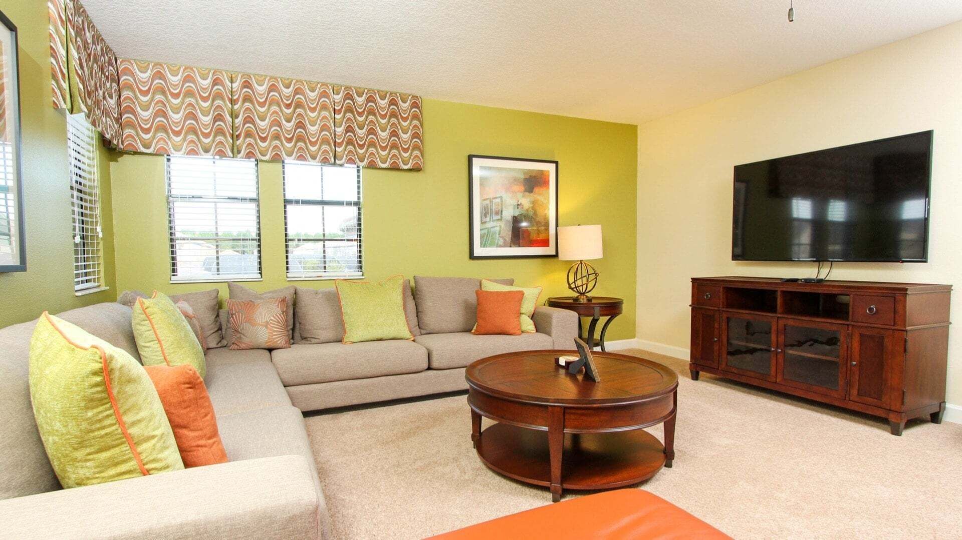 A living room with a sectional sofa, a round coffee table, a TV, and a cabinet.