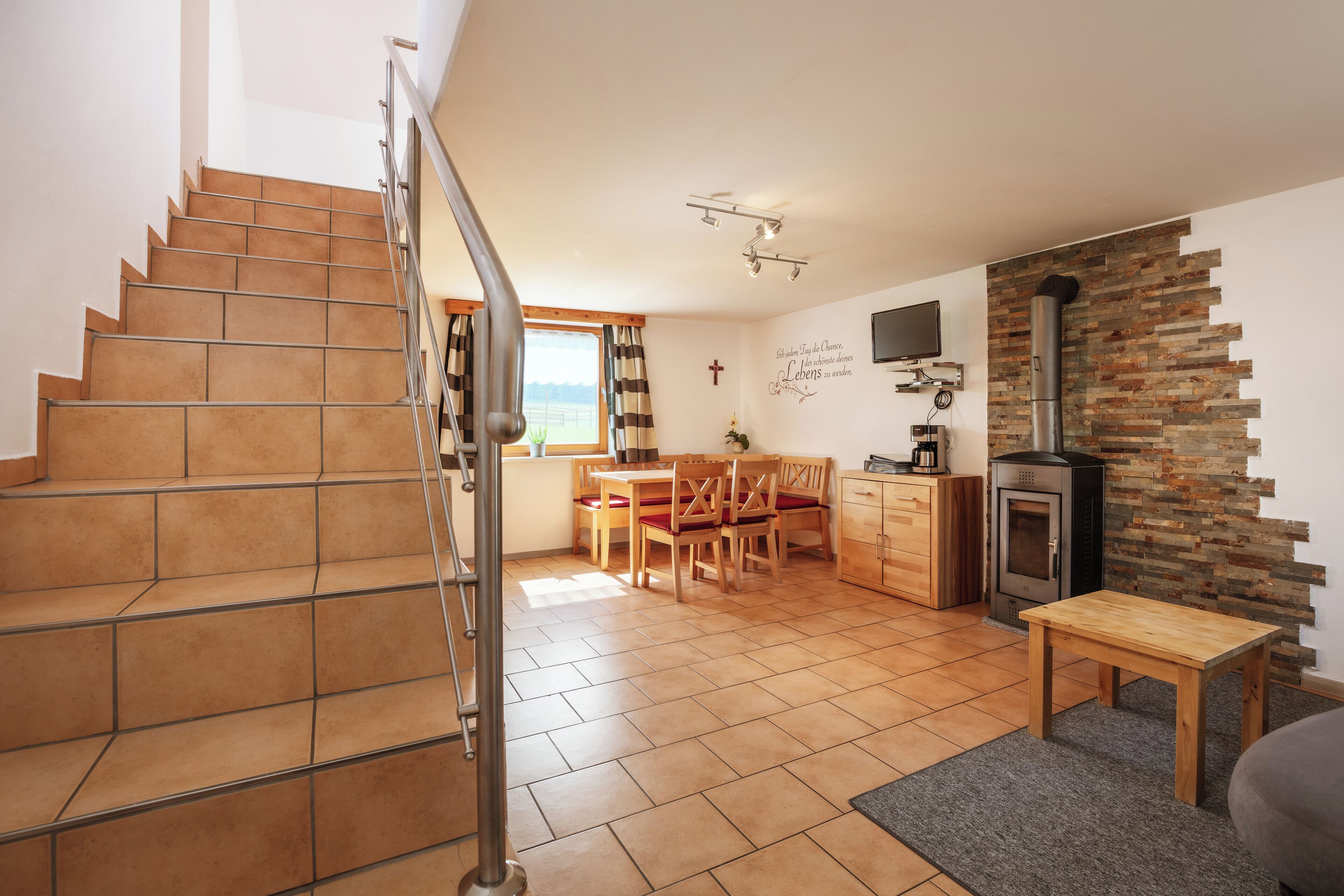 Une cuisine moderne avec une cheminée, un coin repas avec des chaises et une table, et un escalier menant à un autre niveau.