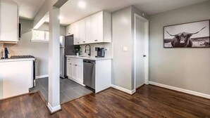 Una cocina moderna con armarios blancos, un refrigerador de acero inoxidable y una cafetera.