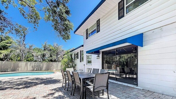 Eine Terrasse mit Pool, Sitzgelegenheiten im Freien und einem überdachten Bereich.
