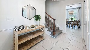 Ein modernes Interieur mit einem Holzkonsolentisch, einer Treppe und einem Essbereich.