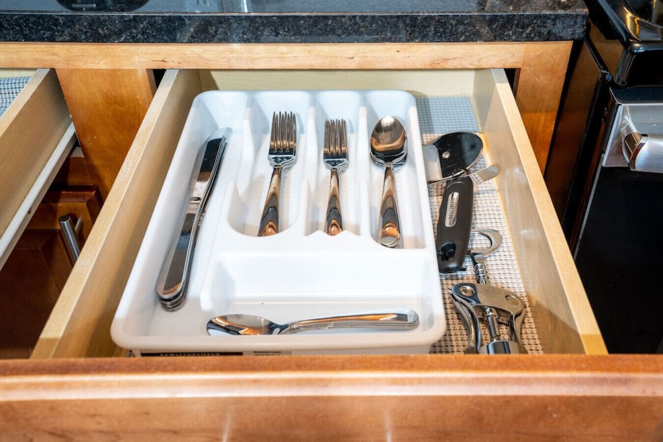 A drawer with a white tray containing cutlery including forks, knives, and spoons.