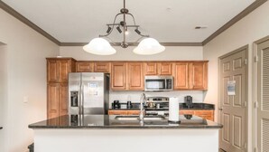 A modern kitchen with wooden cabinets, stainless steel appliances, and a central island. - Affordable 1-bedroom Apartment Keystone (Indianapolis)