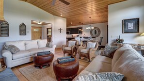 Un salon spacieux comprenant un canapé, des poufs et un coin repas avec des chaises et une table.