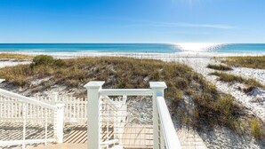 A beach view with a wooden deck and white railings leading to the sand. - Diamond Dunes (Panama City Beach)
