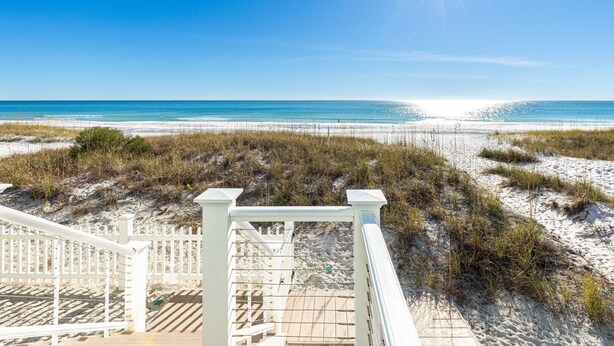 A beach view with a wooden deck and white railings leading to the sand. - Diamond Dunes (Panama City Beach)