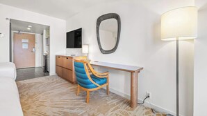 A hotel room with a bed, a desk with a chair, a mirror, a lamp, and a television. - Studio Ocean View & Balcony 1118 (Honolulu)