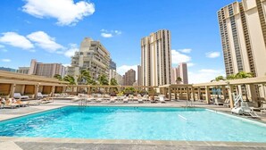 A swimming pool with lounge chairs and a view of tall buildings in the background. - Studio Ocean View & Balcony 1118 (Honolulu)