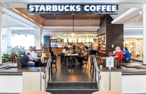 Una cafetería Starbucks dentro de un centro comercial, con zonas de estar y una barra de comida.