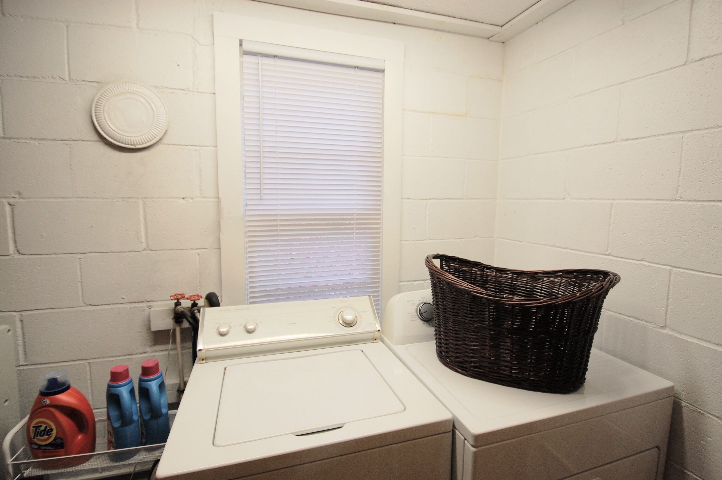 A laundry area with a washing machine, a dryer, and a wicker basket on the dryer.