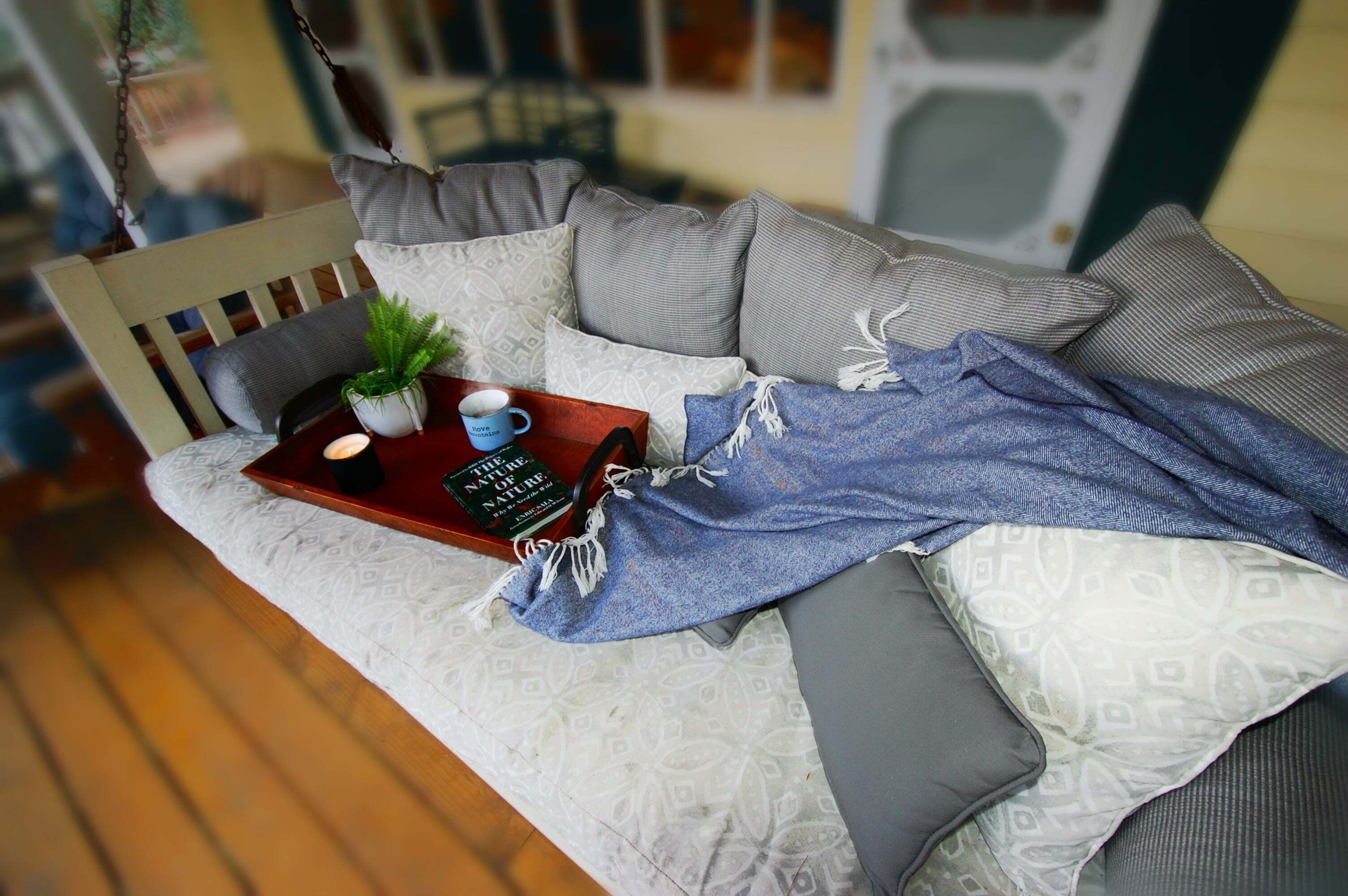 Una sala de estar acogedora con un sofá, una bandeja con un libro, una taza y una planta.