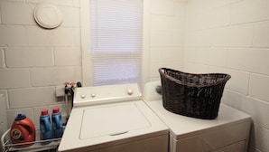 A laundry area with a washing machine, a dryer, and a wicker basket on the dryer. - Highlands Hideout (Highlands)