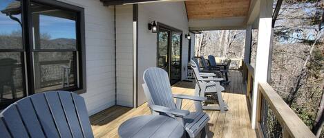 A covered outdoor seating area with Adirondack chairs and a wooden deck.