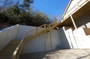 A wooden staircase leading to a building with a concrete foundation and a metal railing. - The Owlery, Walk to Town (Highlands)