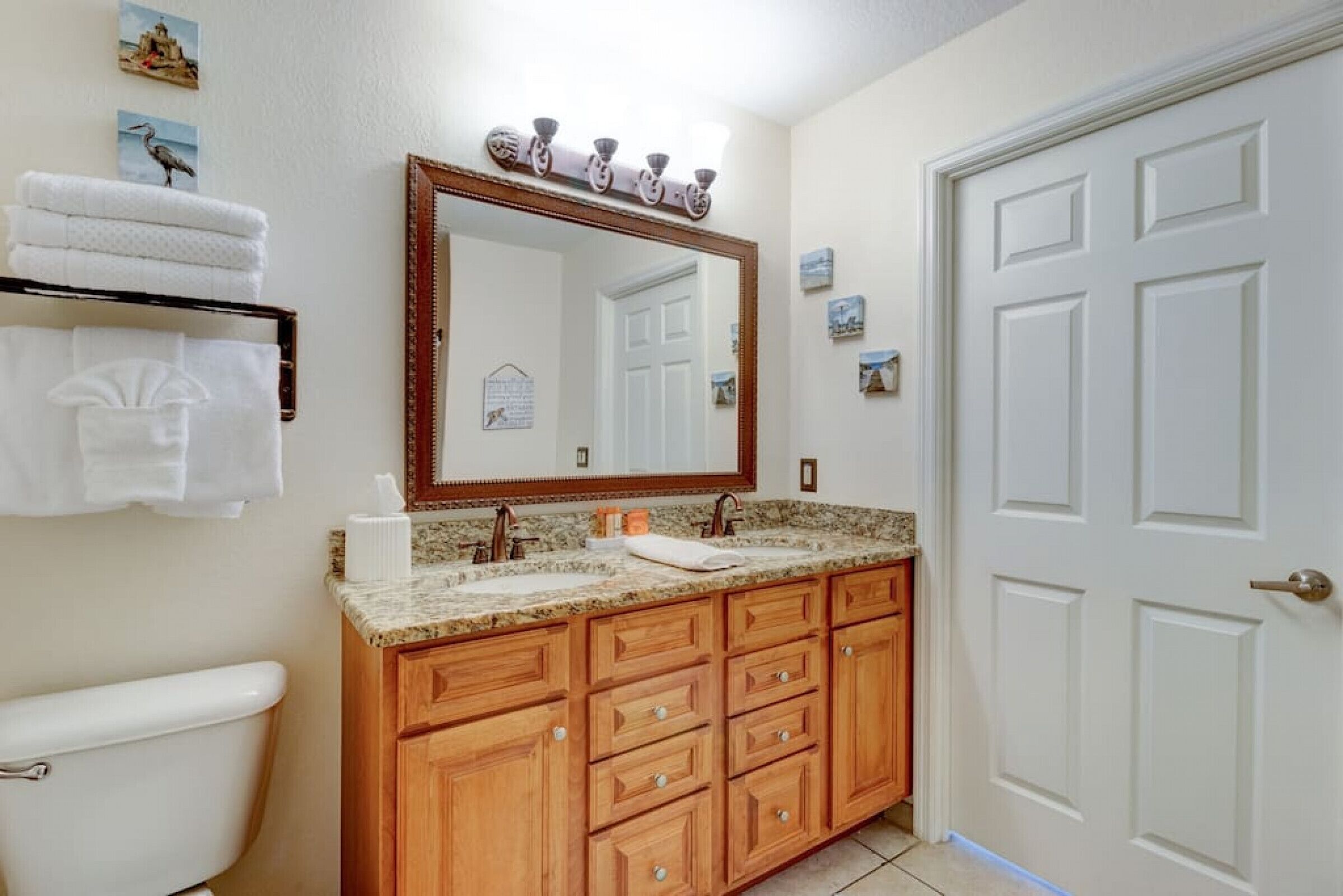 Une salle de bain avec un meuble-lavabo en bois, un grand miroir et une porte blanche.