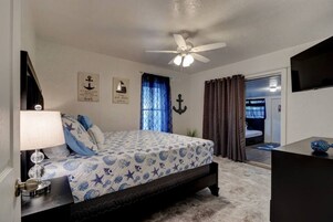 A bedroom with a bed, a ceiling fan, a nightstand, a lamp, and a TV.