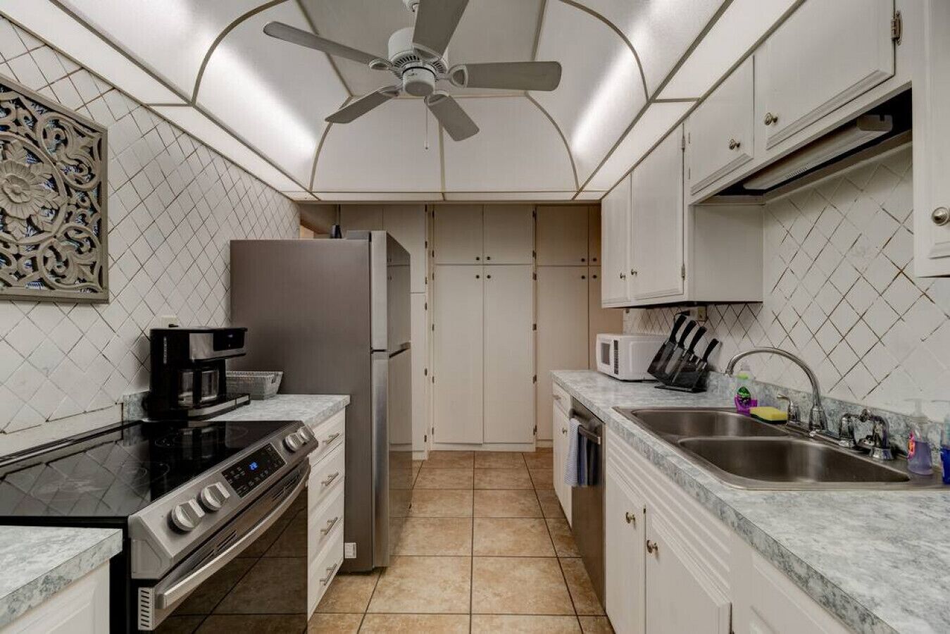 A modern kitchen with a refrigerator, stove, microwave, and sink.