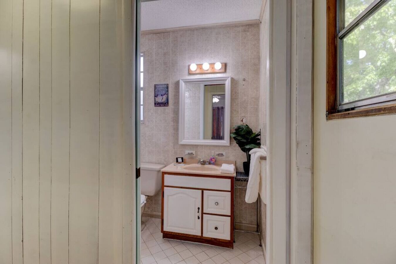 A bathroom with a vanity, a mirror, and a window.