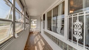 Un pasillo largo y estrecho con amplias ventanas a un lado y una celosía decorativa al otro.