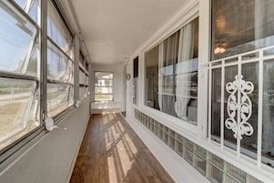 Un pasillo largo y estrecho con amplias ventanas a un lado y una celosía decorativa al otro.