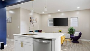 A modern kitchen with a central island, white cabinetry, and a built-in dishwasher. - Modern Comfort Downtown Indy Stylish 3BR Getaway (Indianapolis)