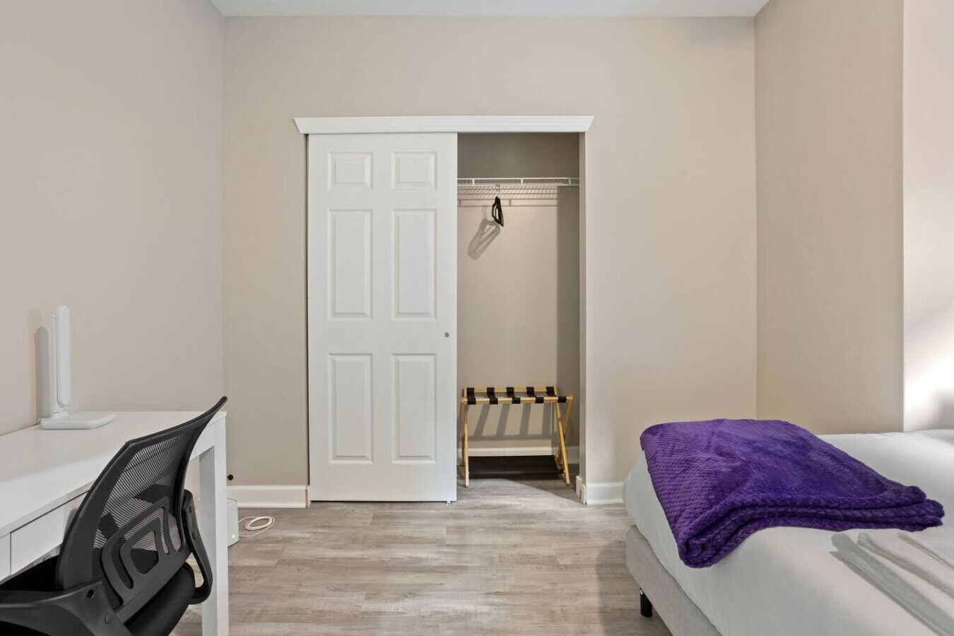 Une chambre à coucher comprenant un lit, un bureau avec une chaise, une armoire et une porte donnant sur une salle de bain.