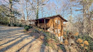 A wooden cabin with a balcony, surrounded by trees and gravel paths. - The Spotted Owl (Highlands)