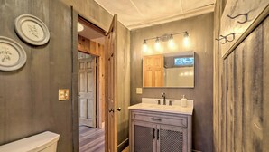 A bathroom with a wooden door, a sink with a mirror, and a toilet. - The Spotted Owl (Highlands)