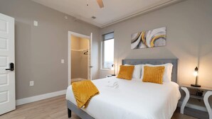 A modern bedroom with a large bed, a walk-in closet, and a view of the city. - Downtown Indy Private Room (Indianapolis)
