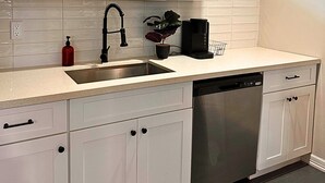 A modern kitchen with white cabinets, a stainless steel dishwasher, and a black faucet. - Modern 2 Bed Near Rice University (Houston)