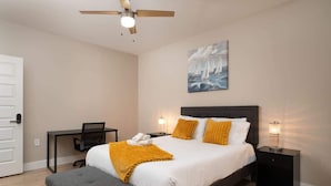 A bedroom with a bed, bedside tables, a desk, a chair, and a ceiling fan. - Downtown Indy Private Room (Indianapolis)