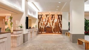 Un hall d’entrée spacieux avec un comptoir d’accueil, un séparateur en bois moderne et un sol recouvert de moquette.