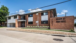 A two-story building with a brick facade, a garage, and a sign reading "URBAN AT MONTROSE 1602". - Spacious Apt Home 6 Min From Medical Center! (Houston)