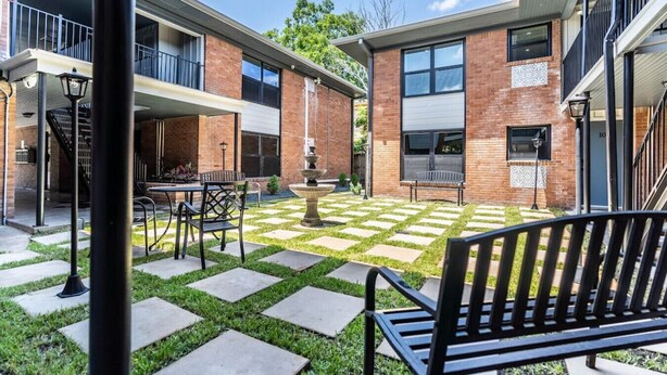 A courtyard with a checkered pattern of grass and stone, outdoor furniture, and a fountain. - Spacious Apt Home 6 Min From Medical Center! (Houston)
