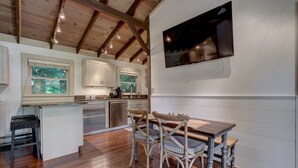 Een moderne keuken met houten balken, een eethoek met een houten tafel en stoelen, en een aan de muur bevestigde televisie.