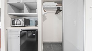 Una kitchenette compacta equipada con microondas, lavavajillas y un refrigerador pequeño.