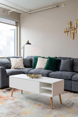 A modern living room with a grey sofa, white coffee table, and a floor lamp. - Downtown Indy Private Room (Indianapolis)