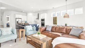 Ein modernes Wohnzimmer mit einer braunen Ledersofa, einem blauen Ohrensessel und einem Couchtisch aus Holz.