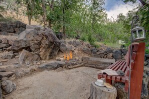 A rustic outdoor seating area with a stone fire pit, wooden benches, and a lantern. - Pecan Point (Hurricane)