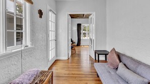 A hallway with a wooden floor, a grey sofa, and a bench. - Spanish Beach Bungalow Mainhouse (Holly Hill)